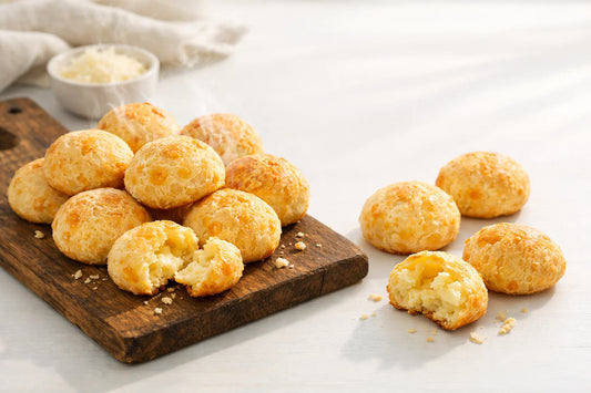 Pão de queijo na Holanda — freshly baked Brazilian cheese breads steaming on a rustic wooden board.
