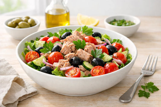 Tuna — a healthy tuna salad in a white ceramic bowl with fresh tomatoes and herbs.