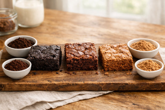Cacaopoeder voor brownies — drie brownies op een rij, elk met een andere kleur en textuur, naast schaaltjes met cacaopoeder.