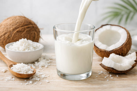 Coconut milk — fresh coconut milk being poured into a glass, with whole coconuts and grated coconut