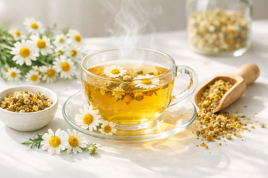 Chamomile tea — steaming cup with fresh chamomile flowers on a clean white surface, promoting relaxation.