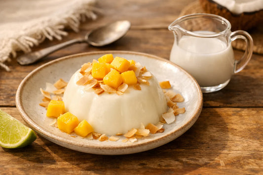 Kokos panna cotta — an elegant dessert on a plate, garnished with toasted coconut flakes and fresh mango cubes.