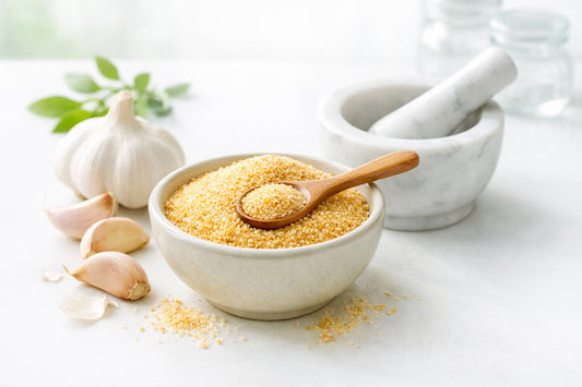 Garlic spice — granulated garlic in a bowl with fresh garlic cloves and a wooden spoon