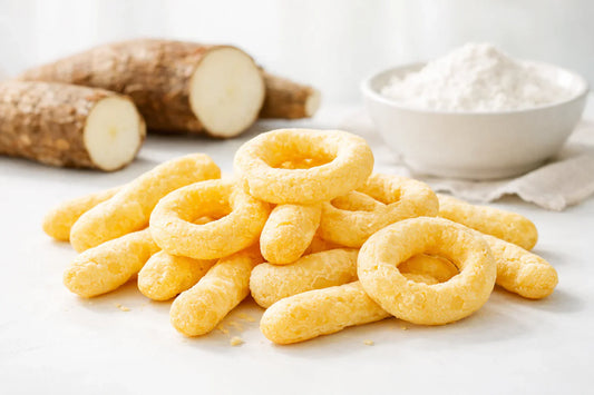 Cassava biscuit — freshly baked biscuits on a white surface with raw cassava root and fermented starch.
