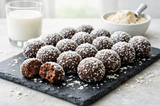 Proteïne snacks — homemade chocolate protein balls rolled in shredded coconut on a slate platter.