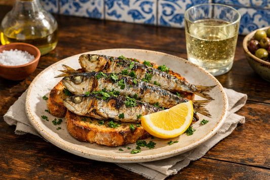 Portugese sardines recepten — een bord met sardines op toast, gegarneerd met verse peterselie en een schijfje citroen.