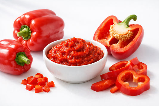 Red Bell Pepper paste — a bowl of vibrant red bell pepper paste with fresh red bell peppers on a white surface