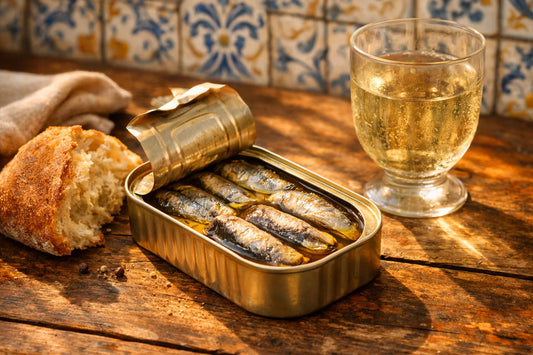 Portugese conservas — an open can of Ramirez sardines on a rustic table with bread and wine.