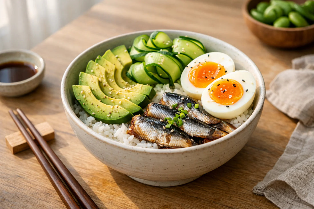 Japanse rijstkom — a colorful Donburi bowl with sardines, avocado, and a soft-boiled egg on a wooden table.