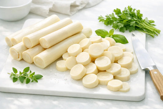 Hearts of Palm — freshly sliced hearts of palm on a white cutting board with green herbs