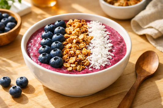 Snelle smoothie bowls — een dikke, paarse bessen smoothie bowl met toppings van granola en vers fruit.
